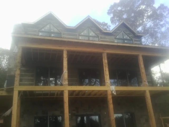 Dormers and porch framing on a large log home under construction — Roof Coating work by our crew in Andersonville