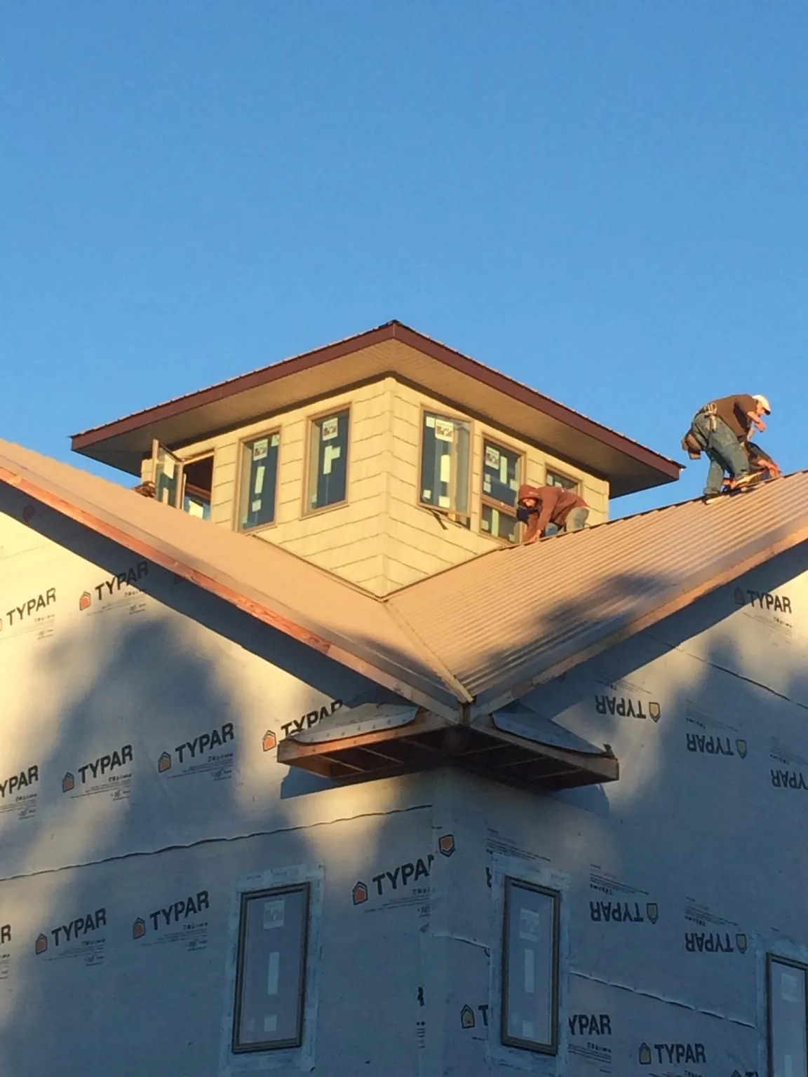 Roofers working around a rooftop cupola on a new metal roof at sunset — Roof Waterproofing in Andersonville by Roofing Brothers